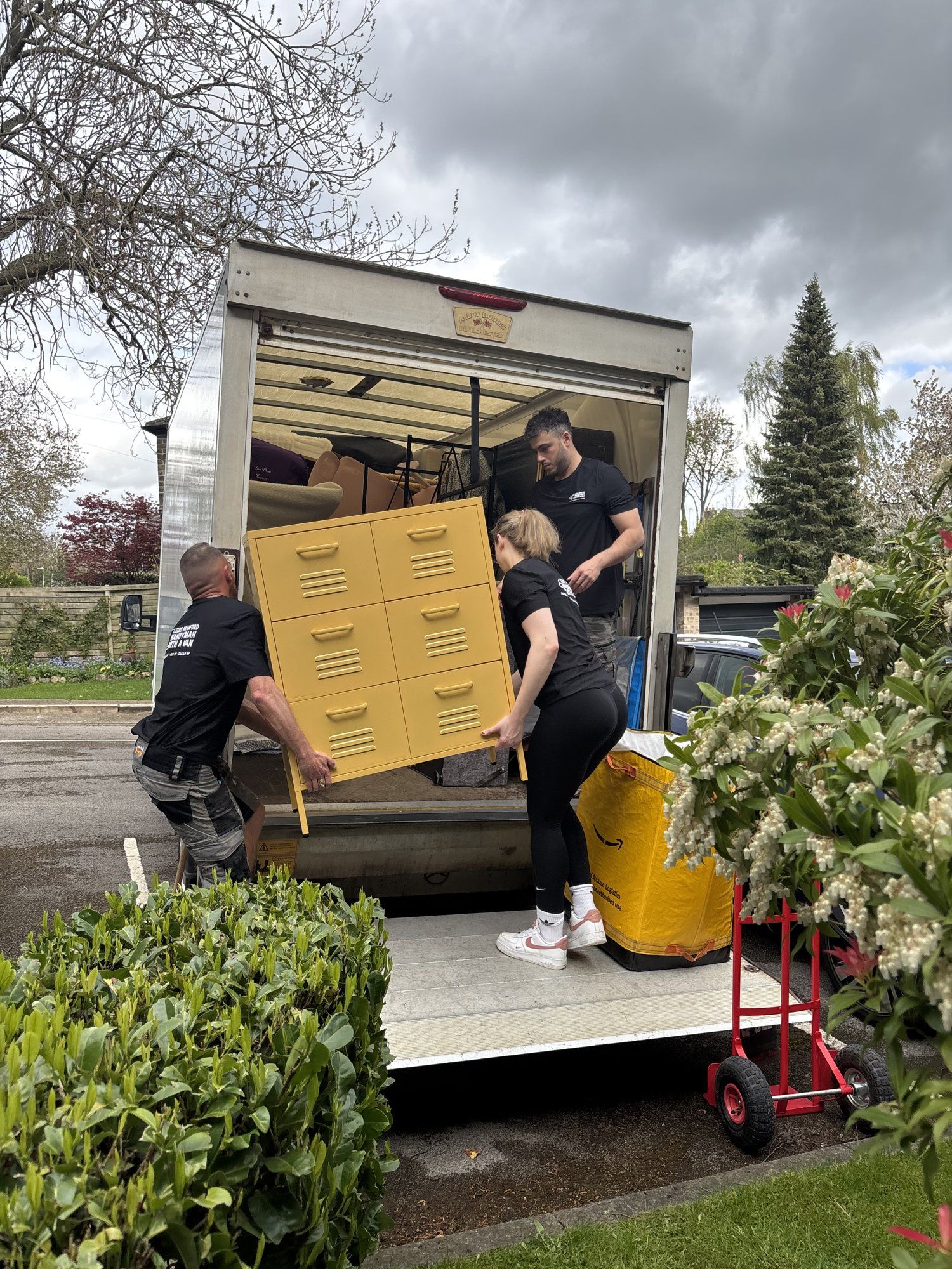 Three crew loading a yellow chest of drawers into the Luton van